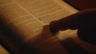 İnananlardan biri İncil 'i masa başında mum ışığında okuyor, ruhani pratikte, yakın çekim, yüksek kalite 4K görüntü.