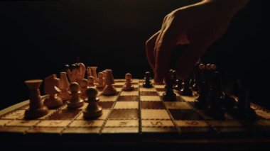 Erkekler satranç oynuyor, turnuvaya katılıyor, klasik ahşap satranç tahtası ve sayaç ışığı, piyon hareketi, stratejik masa oyunu, yakın çekim, yüksek kalite 4k görüntü