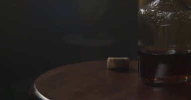 Kırsal bir masa üzerinde çarpıcı bir viski şişesi yumuşak, davetkar bir atmosfer yaratır. Rahatlamak için mükemmel.