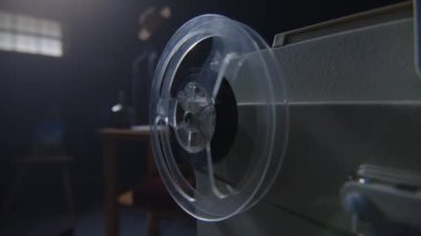 Bu görüntü, karamsar ve atmosferik bir iç mekan içerisindeki reeltoreel kaset çaların yakın çekimini yakalar.