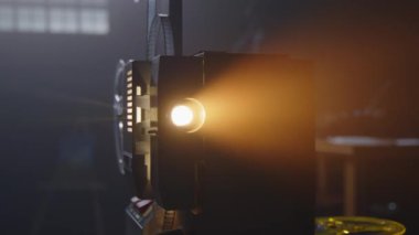 Klasik bir film projektörü, ekranda loş bir alanda yumuşak bir ışık saçıyor.
