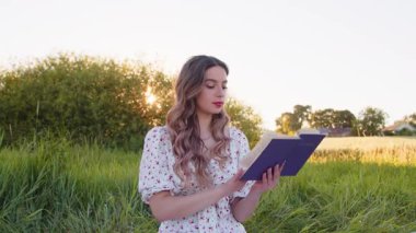 Genç bir kadın gün batımının büyüleyici parıltısının tadını çıkarırken büyüleyici bir kitapta neşe ve rahatlık bulur.