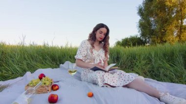 Canlı çiçekler ve yeşilliklerle dolu huzurlu bir tarlada büyüleyici bir kitap okuyan bir kadın.