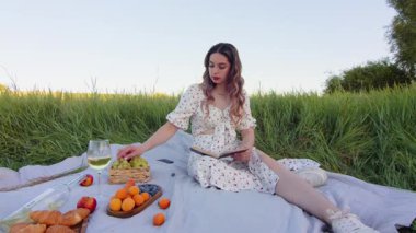 Yeşillik bir tarlanın ortasında keyifli bir pikniğin tadını çıkar. Harika bir kitap okurken lezzetli atıştırmalıkların tadını çıkar.