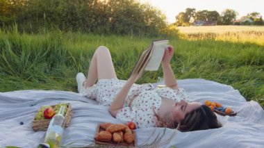 Güzel bir tarlada okuma materyalleri ve lezzetli atıştırmalıklar içeren sakin ve davetkar bir piknik düzeneği.