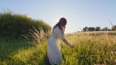 Kaygısız ve neşeli genç bir kadın çarpıcı bir tarlayı keşfediyor. Gökyüzünün altındaki sıcak güneş ışığının tadını çıkarıyor.