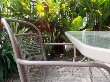 Bahçe masası ve sandalyeler yeşillikle çevrili.