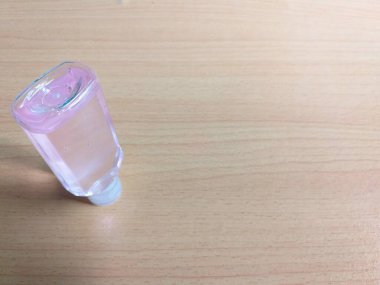 30 ml baş aşağı duran el dezenfektanı, fotokopi alanı için ahşap arka plan, köşegen açıyla çekim.