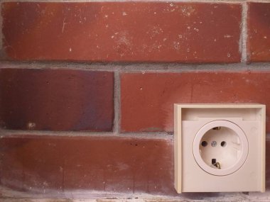 Tuğla bir duvarda beyaz elektrik prizi, ev yenileme, elektrik tesisatı, inşaat projeleri, elektrik bakımı ve iç tasarım için ideal.