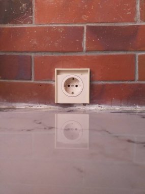 Beyaz elektrik prizi kırmızı tuğla duvara monte edilmiş. Elektrik hizmetleri, ev geliştirme, inşaat ve iç tasarım kavramları için uygundur.