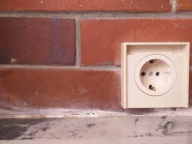 Kırmızı duvarda beyaz elektrik prizi var. Ev geliştirme, inşaat, elektrik işi, yenileme, iç tasarım, endüstriyel kavramlar için elverişli.