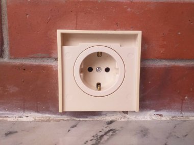 Kırmızı tuğla duvara monte edilmiş beyaz elektrik prizi, pazarlama malzemelerinde ev geliştirme veya elektrik tedarik kavramları için uygundur.