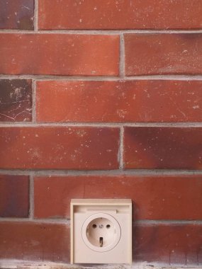 Kırmızı bir duvardaki beyaz bir elektrik prizinin portresi. Ev geliştirme, elektrik hizmetleri, inşaat ve mimari projeleri için elverişli.