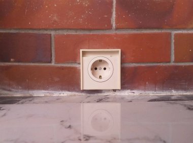 Tuğla duvardaki beyaz elektrik prizi, konut ve ticari alan tasarımı kavramının temel arşivlerinden biri. Teknoloji temaları.