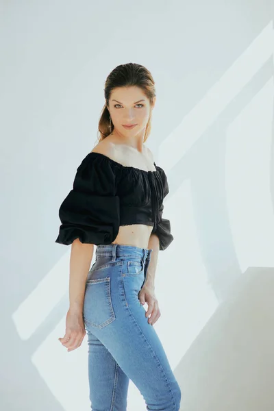 美しいスリム若いですCaucais女性で黒花とジーンズ上の白い背景で写真スタジオ — ストック写真