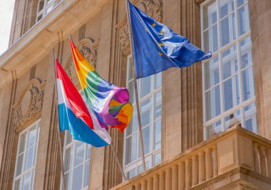 European Union, LGBTQ+ and Luxembourgish flags tigether at the building. Esch-Sur-Alzette, Luxembourg - July 08, 2023 - Luxembourg Pride. Equality March. clipart