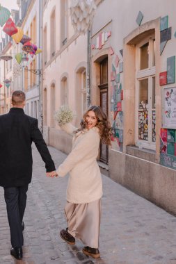 Kışın büyüleyici bir Avrupa şehrinde yürüyen neşeli bir çift. Düğün, aşk, sokak tarzı