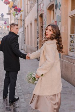 Kışın büyüleyici bir Avrupa şehrinde yürüyen neşeli bir çift. Düğün, aşk, sokak tarzı