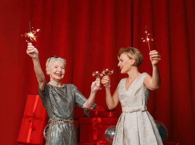 Havai fişek ve yeni yılı kutlayan gözlüklü, şık, olgun iki son sınıf kadını. Mutlu Gece Yılı 2025