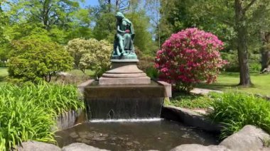 Şehir parkında güzel bir çeşme var. Parktaki güneş çeşmesi. Bahçedeki güzel çiçekler. Mavi gökyüzü. Yaz zamanı. Açık yeşil gizli bahçe. İnanılmaz doğa, yeşil üçlüler. Danimarka, Viborg