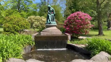 Şehir parkında güzel bir çeşme var. Parktaki güneş çeşmesi. Bahçedeki güzel çiçekler. Mavi gökyüzü. Yaz zamanı. Açık yeşil gizli bahçe. İnanılmaz doğa, yeşil üçlüler. Danimarka, Viborg