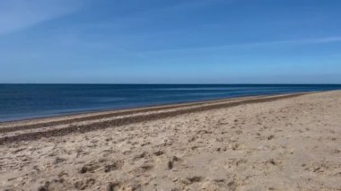 Baltık sahili kum tepeleri, fırtınadan sonra plaj. Gün batımı, yumuşak altın güneş ışığı, parlayan bulutlar. Doğa, çevre, ekoloji, eko-turizm, yürüyüş, keşif kavramları. Jutland Danimarka. Çevre turizmi.