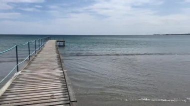 Açık gökyüzüne karşı ahşap iskele. Yüksek kalite 4K görüntü. Kuzey Denizi boyunca kum tepelerinin manzarası. Baltık Denizi 'nin Danimarka kıyılarında nefes kesici bir manzara. Bulutlar ve güneş denizin ve iskelenin üzerinde. 