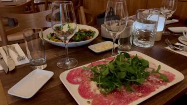 Carpaccio bifteği, parmesanlı soğuk aperatif kapari ve beyaz tabakta roka. Üst Manzara. Restoran menüsü. Lüks yemekler. Bir gurme et carpaccio ve parmesan peyniri. İtalyan yemek başlatıcısı. 