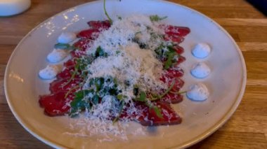 Carpaccio bifteği, parmesanlı soğuk aperatif kapari ve beyaz tabakta roka. Üst Manzara. Restoran menüsü. Lüks yemekler. Bir gurme et carpaccio ve parmesan peyniri. İtalyan yemek başlatıcısı. 