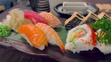 Suşi ve rulo ekmek. Dikdörtgen suşi tabağında suşi ruloları yakın plan. Bir tabak dolusu taze suşi, somon, avokado ve yemek çubuklarıyla servis edilen siyah sushi tohumları. Japon deniz ürünleri 