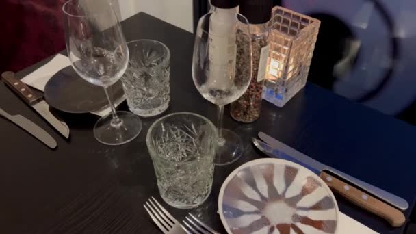 高級レストランでのダイニングテーブル テーブルの上の水ジャグおよび飲むガラス ワイングラスとナプキン付きのレストランテーブル テーブルにプレートとカトラリー付きのロマンチックなディナーの場所設定 — ストック動画