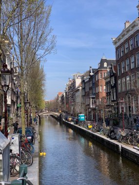 Amsterdam şehir merkezi - Amstel nehri, eski evler ve bir köprü. Meşhur Amsterdam şehrinin güzel manzarası. Avrupa 'ya seyahat. Hollanda, Hollanda. Geleneksel Hollanda eski evleri. Amsterdam Bisikletleri 