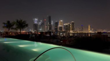 Dubai Palm Jumeirah adalarının gece manzarası. Geceleri gökdelen. Güzel havuz ve kumsal. Geceleri Dubai Marina 'da Palm Jumeirah Adaları' nın gölündeki aydınlık binalar ve yansımalarla. Lüks. 