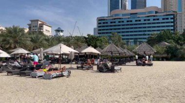 Dubai Jumeirah plajı, BAE 'de marina gökdelenleri var. Dubai Marina bölgesinde ikonik gökdelenler manzaralı lüks kumlu bir sahil. Plajlar ve Dubai göz teması gün batımında tekne ve yatlarla.