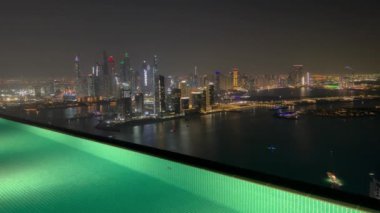Dubai Palm Jumeirah adasının havadan görünüşü, Birleşik Arap Emirlikleri. Geceleri AURA gökyüzü barında dinlenen turistler, Palm Jumeirah 'daki Dubai Marina manzaralı dünyanın en yüksek 360 derecelik sonsuz havuzu.