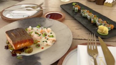 Suşi ve balığın yakın plan çekimi. Servis tabağında somon. Tabakta yemek, masada yemek, lezzetli yiyecekler, lezzetli yiyecekler. Suşi seti ve suşi. Restoranda hizmet etmek. 