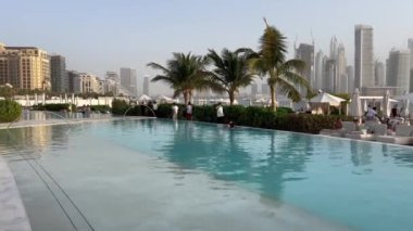 Dubai Palm Jumeirah adalarının manzarası. Sahile yakın lüks havuzlar. Dubai Jumeirah plajı ve BAE 'de Marina gökdelenleri. Arka planda Marina ve şehir merkezindeki gökdelenlerin bulunduğu Palm Jumeirah binaları.