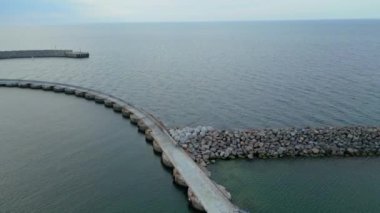 Danimarka 'daki Hanstholm Havn manzarası. Deniz kıyısının yüksek açılı manzarası. Taştan kaya iskeleden yapılmış deniz suyu, güneş ışığı anteninden. Sabahları dalgalar alçaldığında havadan uzun dalgalar görülür. Sahildeki kayaların havadan görünüşü 
