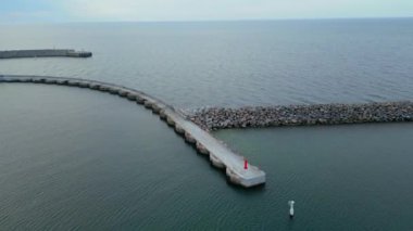 Danimarka 'daki Hanstholm Havn manzarası. Deniz kıyısının yüksek açılı manzarası. Taştan kaya iskeleden yapılmış deniz suyu, güneş ışığı anteninden. Sabahları dalgalar alçaldığında havadan uzun dalgalar görülür. Sahildeki kayaların havadan görünüşü 