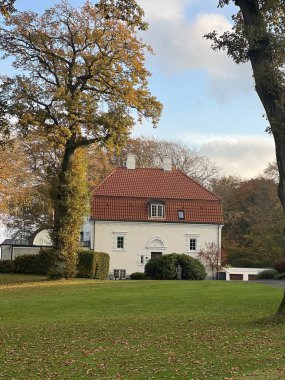 White houses with a red roof in the town, Colorful golden sunset sky calmness tranquil relaxing sunlight summer vibes. Park like private garden. Path in the forest. Skive clipart