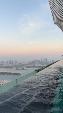 Dubai Palm Jumeirah adasının havadan görünüşü, Birleşik Arap Emirlikleri. AURA gökyüzü barında dinlenen turistler Dubai Jumeirah Marina ufuk çizgisindeki dünyanın en yüksek 360 derecelik sonsuz havuzu. Dikey video