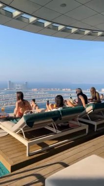 Dubai, BAE - 2 Haziran 2025: Dubai Palm Jumeirah adasının havadan görünüşü, AURA gökyüzü barında dinlenen turistler, Palm Jumeirah 'daki dünyanın en yüksek 360 derecelik sonsuz havuzu. Dikey video. Afiyet olsun