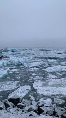 Jokulsarlon sahilinde siyah kumlu buz kayası. İzlanda 'daki Diamond Sahili' ndeki buzdağları. Siyah kumsalda donmuş buz. Jokulsarlon Vatnajokull Ulusal Parkı 'nda güzel bir buzul gölü. Doğa 