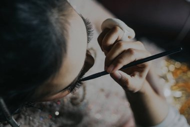 Yukarıdan bakıldığında, bir makyöz birine kaş uyguluyor.