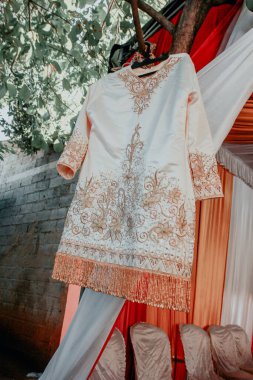 Gelinin geleneksel elbisesi bir ağaç dalında asılı.