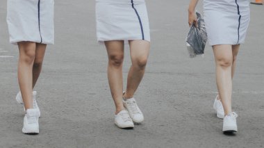 Beyaz elbiseler ve beyaz spor ayakkabılar giyen üç kişinin yakın çekim görüntüsü.