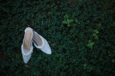 Gelinin ayakkabısının yüksek açısı yerdeki yabani bitkilerin üstünde.