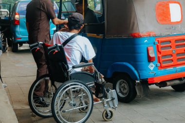 Toplu taşımaya binmek üzere olan engelli bir kişinin arka görüntüsü