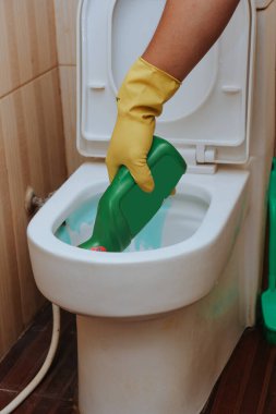 Tuvaleti temizleyen ellerin yakın çekimi.