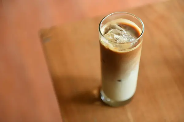 Iced coffee milk with palm sugar on wooden table.